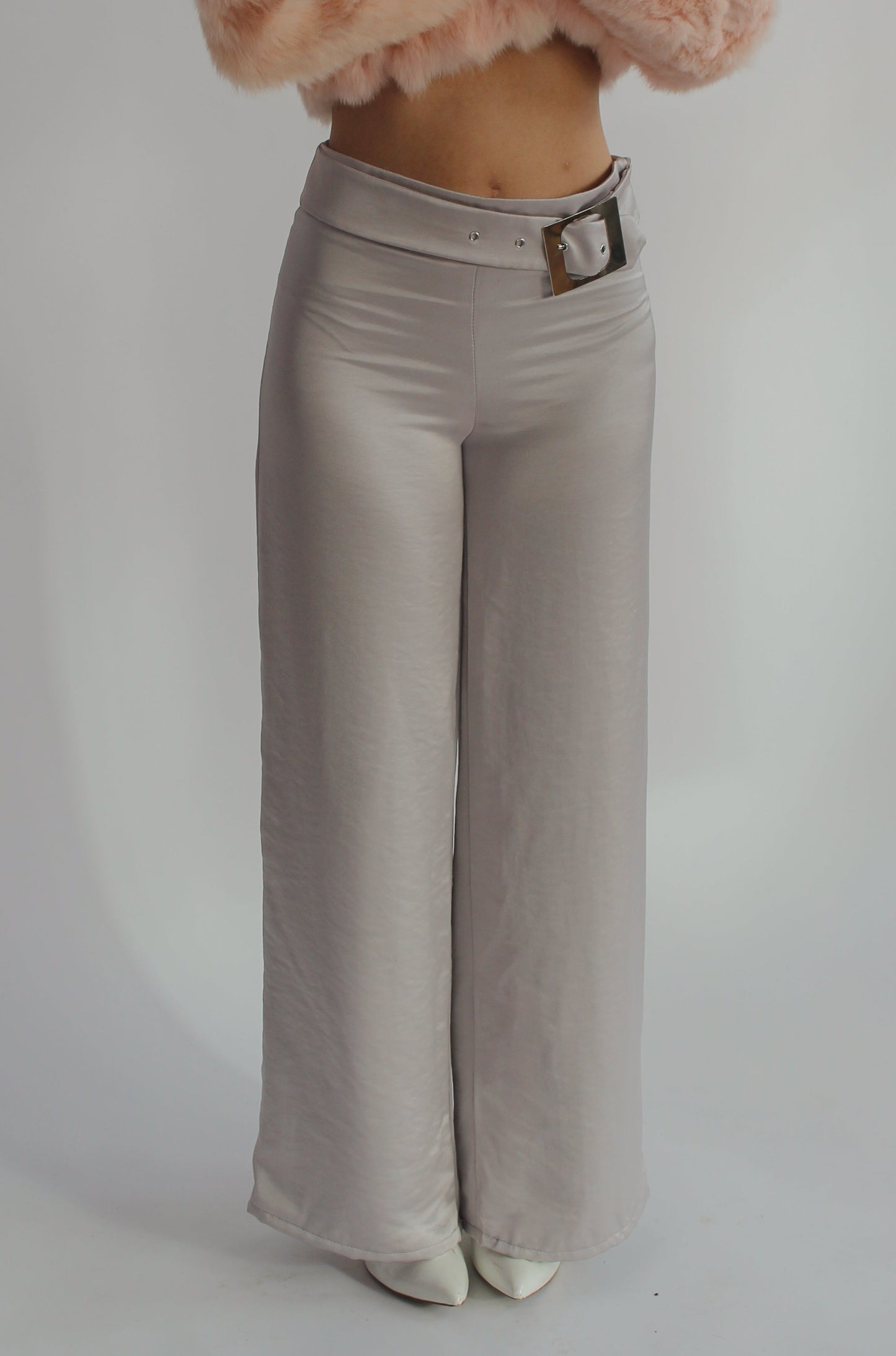 Woman wearing silver silk pants on a white background